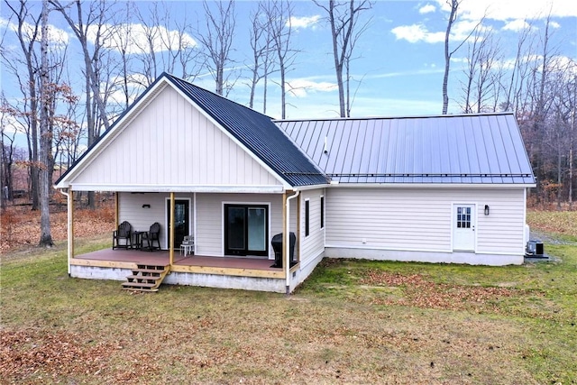 rear view of house featuring a lawn and covered porch