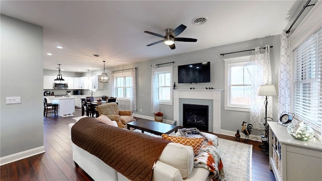 living room featuring a tile fireplace, dark hardwood / wood-style flooring, and ceiling fan