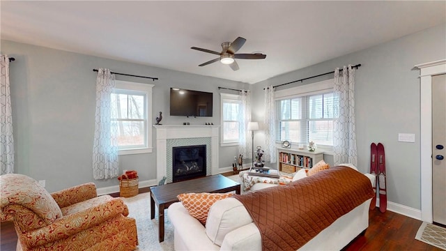 living room featuring a tile fireplace, ceiling fan, dark hardwood / wood-style flooring, and plenty of natural light