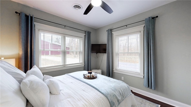 bedroom featuring multiple windows, hardwood / wood-style floors, and ceiling fan