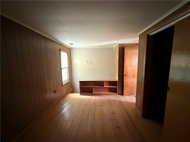 hall featuring wood walls, crown molding, hardwood / wood-style floors, and a textured ceiling