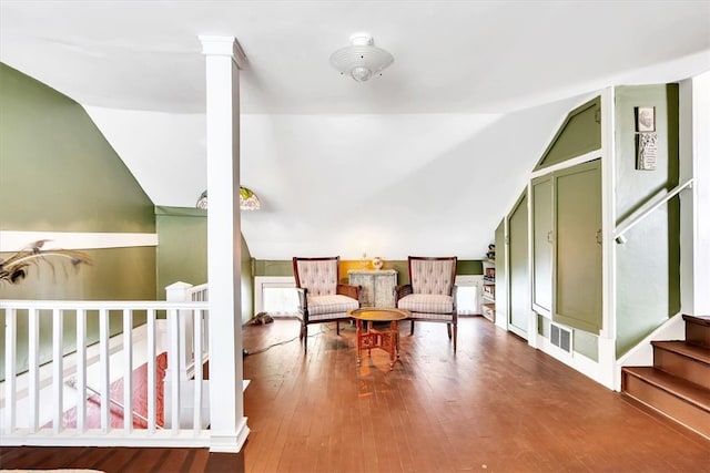 sitting room featuring vaulted ceiling, wood-type flooring, and ornate columns