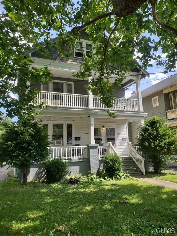 view of front of property featuring a balcony and a front lawn