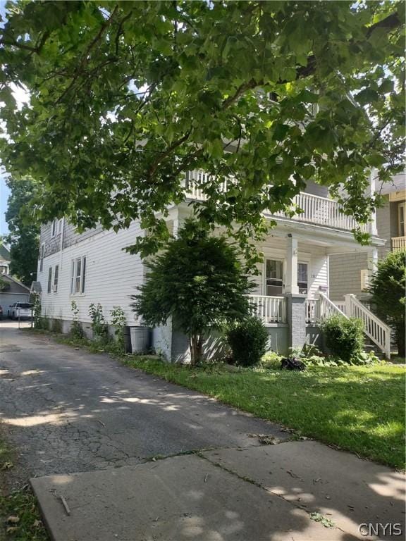 view of side of property with covered porch and a lawn