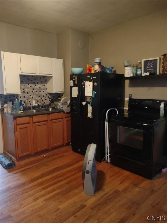 kitchen featuring white cabinetry, sink, decorative backsplash, hardwood / wood-style flooring, and black appliances