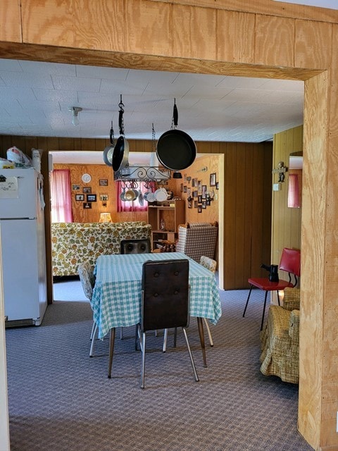 dining room with wooden walls and dark colored carpet