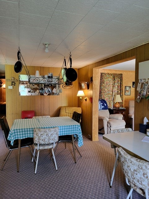 carpeted dining space with wood walls