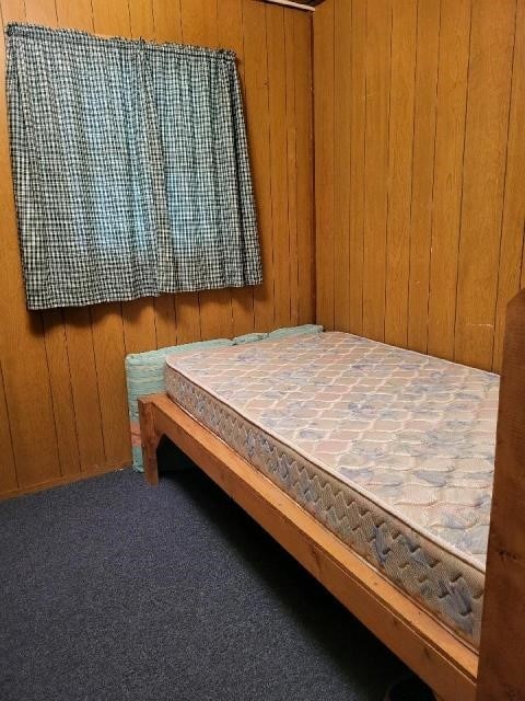 carpeted bedroom featuring wooden walls