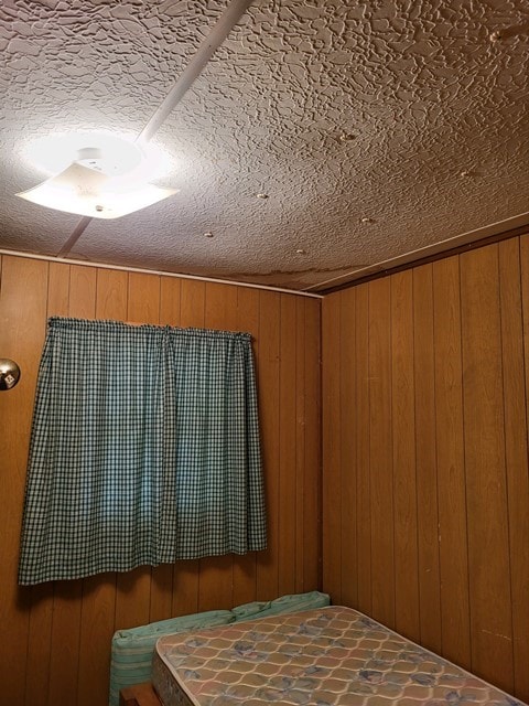 unfurnished bedroom with wood walls and a textured ceiling