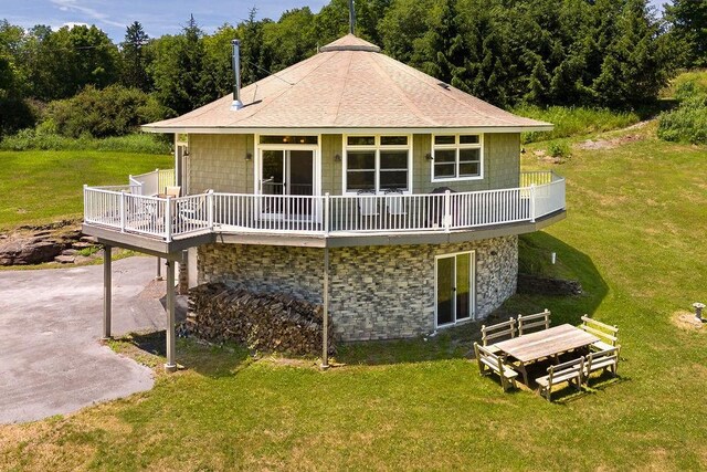 rear view of house with a wooden deck, a patio, and a lawn