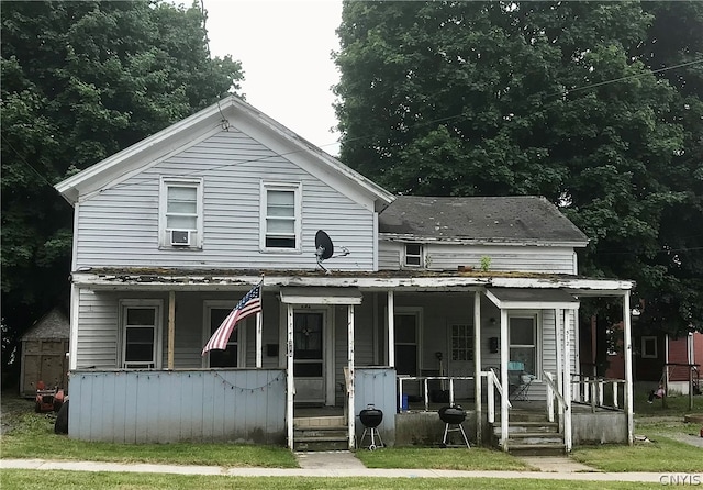 view of front facade featuring a porch, a front lawn, and cooling unit