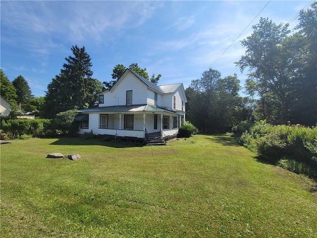 view of side of property featuring covered porch and a lawn