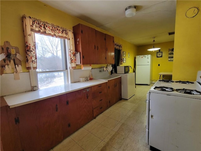 kitchen with decorative light fixtures, white appliances, and washer / dryer