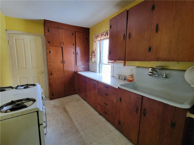 kitchen featuring white range with gas stovetop, kitchen peninsula, and sink