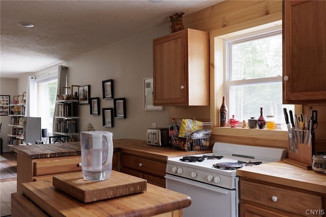 kitchen with butcher block countertops, white gas stove, and a textured ceiling