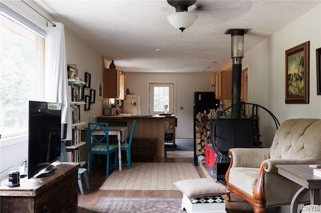 living room with a wood stove, light hardwood / wood-style flooring, and a textured ceiling