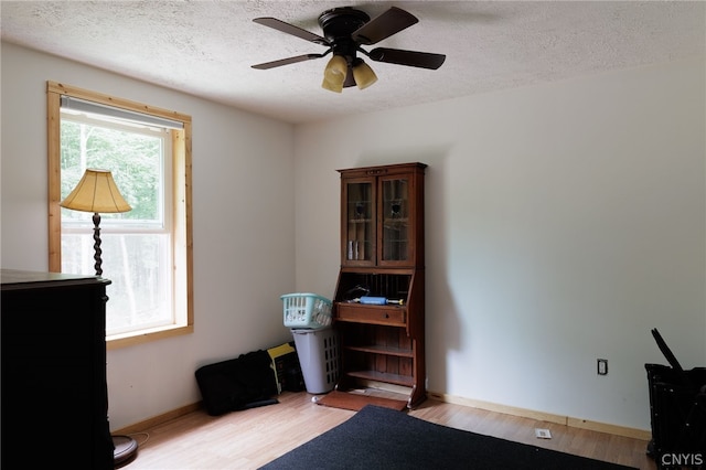 miscellaneous room featuring ceiling fan, light hardwood / wood-style flooring, and a textured ceiling