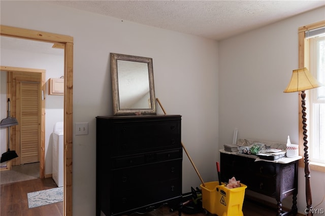 bedroom with a textured ceiling, dark hardwood / wood-style flooring, and washer and dryer