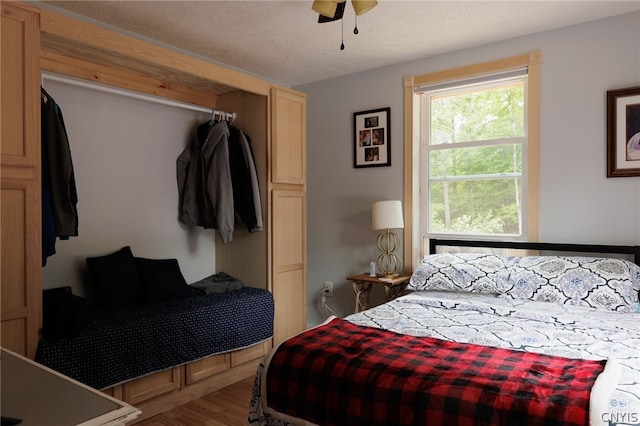 bedroom with ceiling fan, hardwood / wood-style floors, and a textured ceiling