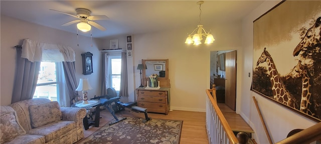 living room with ceiling fan with notable chandelier and light hardwood / wood-style floors