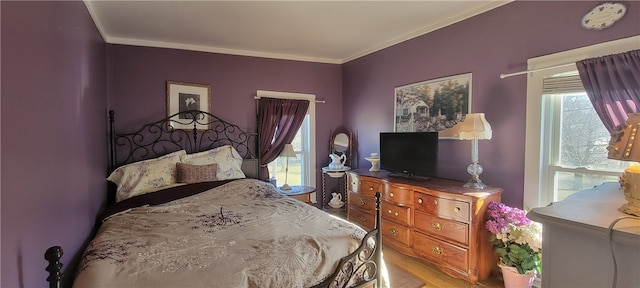 bedroom featuring multiple windows, light wood-type flooring, and crown molding