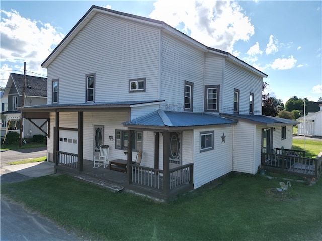 rear view of house featuring a porch, a garage, and a yard