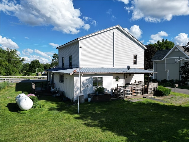 back of property featuring a wooden deck and a lawn