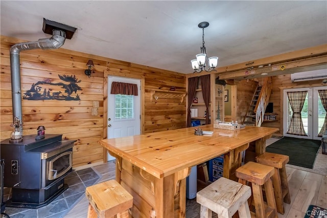 dining area featuring wood walls, dark hardwood / wood-style flooring, a wall mounted AC, and a wood stove