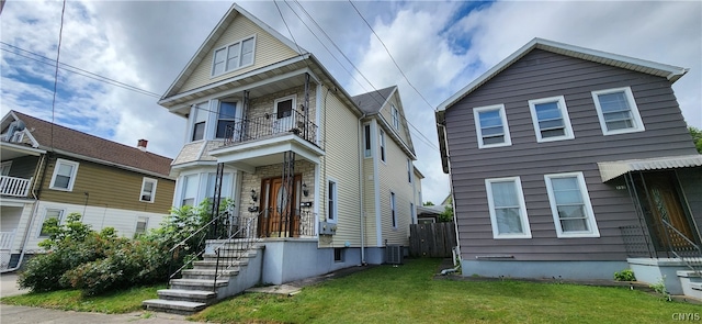 front facade with a balcony, central air condition unit, and a front lawn