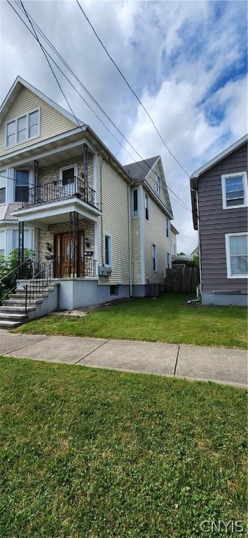 rear view of property featuring a balcony and a lawn