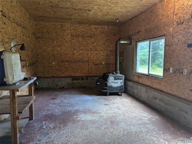 unfurnished room featuring concrete flooring and a wood stove