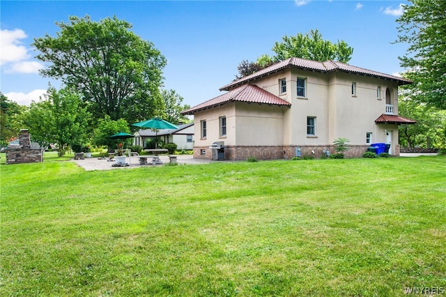 back of house with a lawn, a patio area, and a fireplace