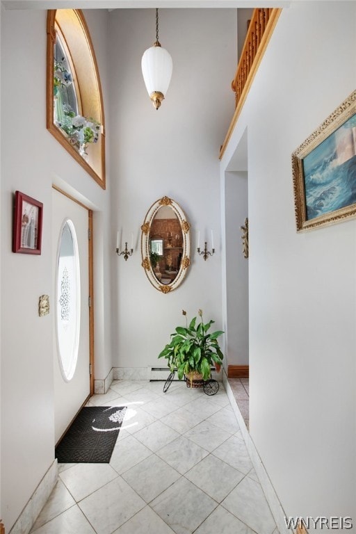 entrance foyer featuring a high ceiling, light tile patterned flooring, and baseboard heating