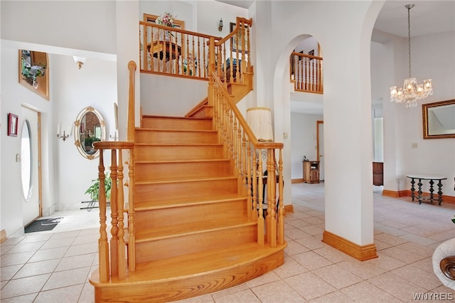 staircase featuring a high ceiling, tile patterned flooring, and a chandelier