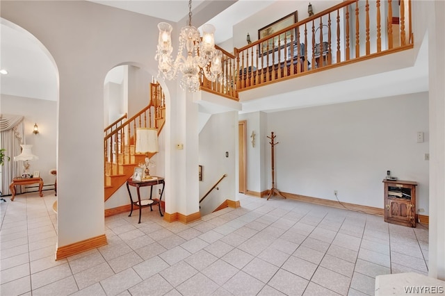 interior space featuring a towering ceiling, light tile patterned flooring, a baseboard heating unit, and a notable chandelier