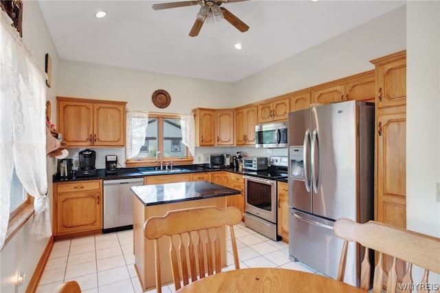 kitchen with sink, a center island, light tile patterned flooring, ceiling fan, and appliances with stainless steel finishes