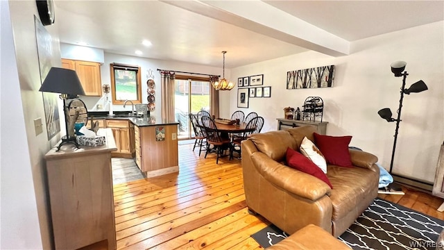 living room with beam ceiling, light hardwood / wood-style flooring, an inviting chandelier, and sink