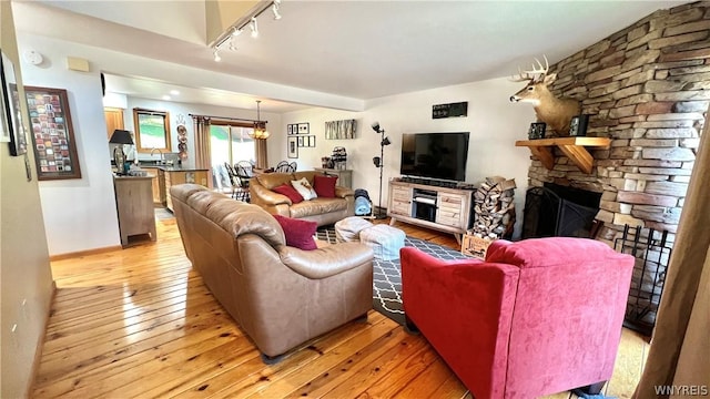 living room featuring a fireplace, light hardwood / wood-style floors, and track lighting