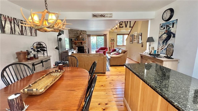 dining room featuring an inviting chandelier, a stone fireplace, and light hardwood / wood-style flooring