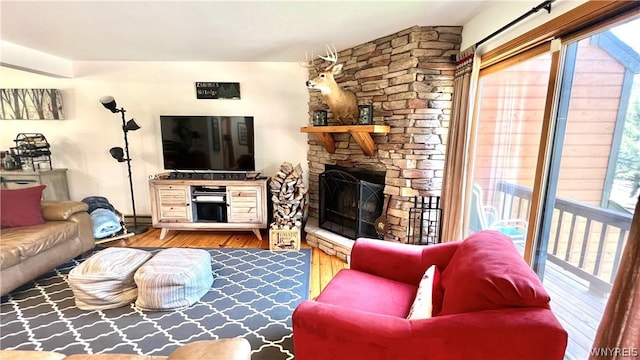 living room featuring a fireplace, wood-type flooring, and a healthy amount of sunlight