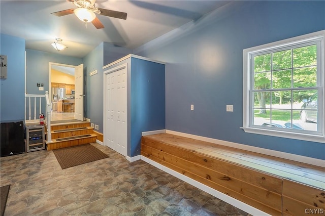 mudroom featuring plenty of natural light, wine cooler, stone finish floor, and a ceiling fan