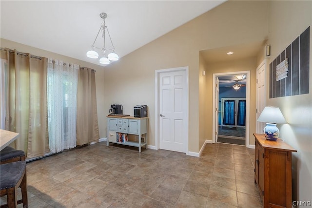 dining area featuring ceiling fan, vaulted ceiling, stone finish floor, and baseboards