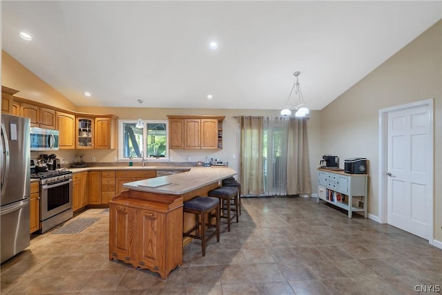 kitchen with a center island, lofted ceiling, appliances with stainless steel finishes, a kitchen bar, and a chandelier