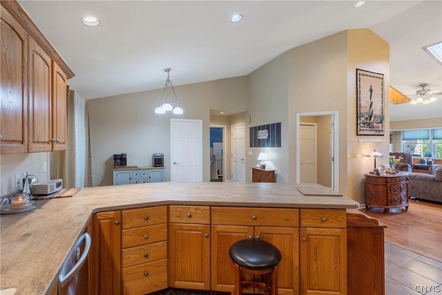 kitchen featuring pendant lighting, ceiling fan with notable chandelier, kitchen peninsula, and vaulted ceiling