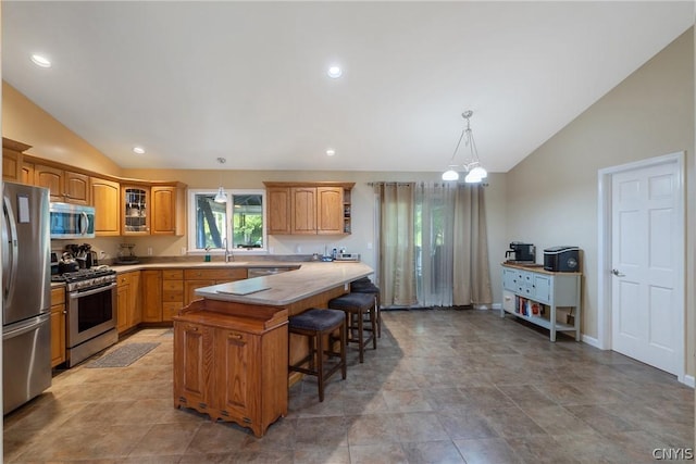 kitchen featuring a center island, pendant lighting, vaulted ceiling, a kitchen bar, and appliances with stainless steel finishes