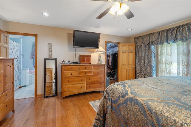 bedroom with light wood-type flooring, a walk in closet, ensuite bathroom, ceiling fan, and a closet