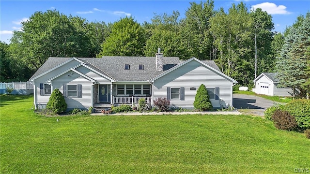 back of property with roof with shingles, a porch, a chimney, a lawn, and an outdoor structure