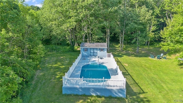 view of pool featuring a wooded view, fence, an outbuilding, a yard, and a fenced in pool