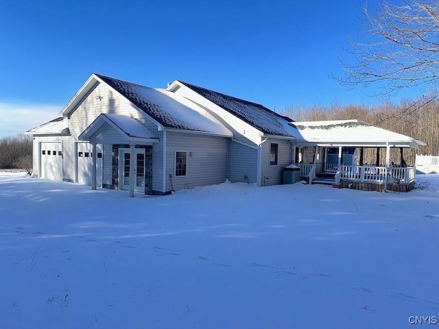 view of snowy exterior with a porch and a garage