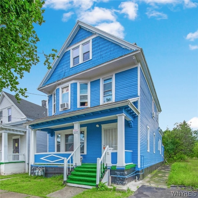 view of front facade featuring a porch, cooling unit, and a front yard